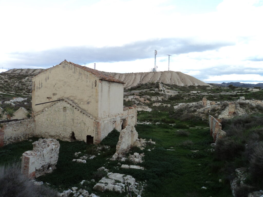 Imagen actual del antiguo edificio de almacenamiento del azufre, con el paisaje de fondo de la mina ya abandonada.